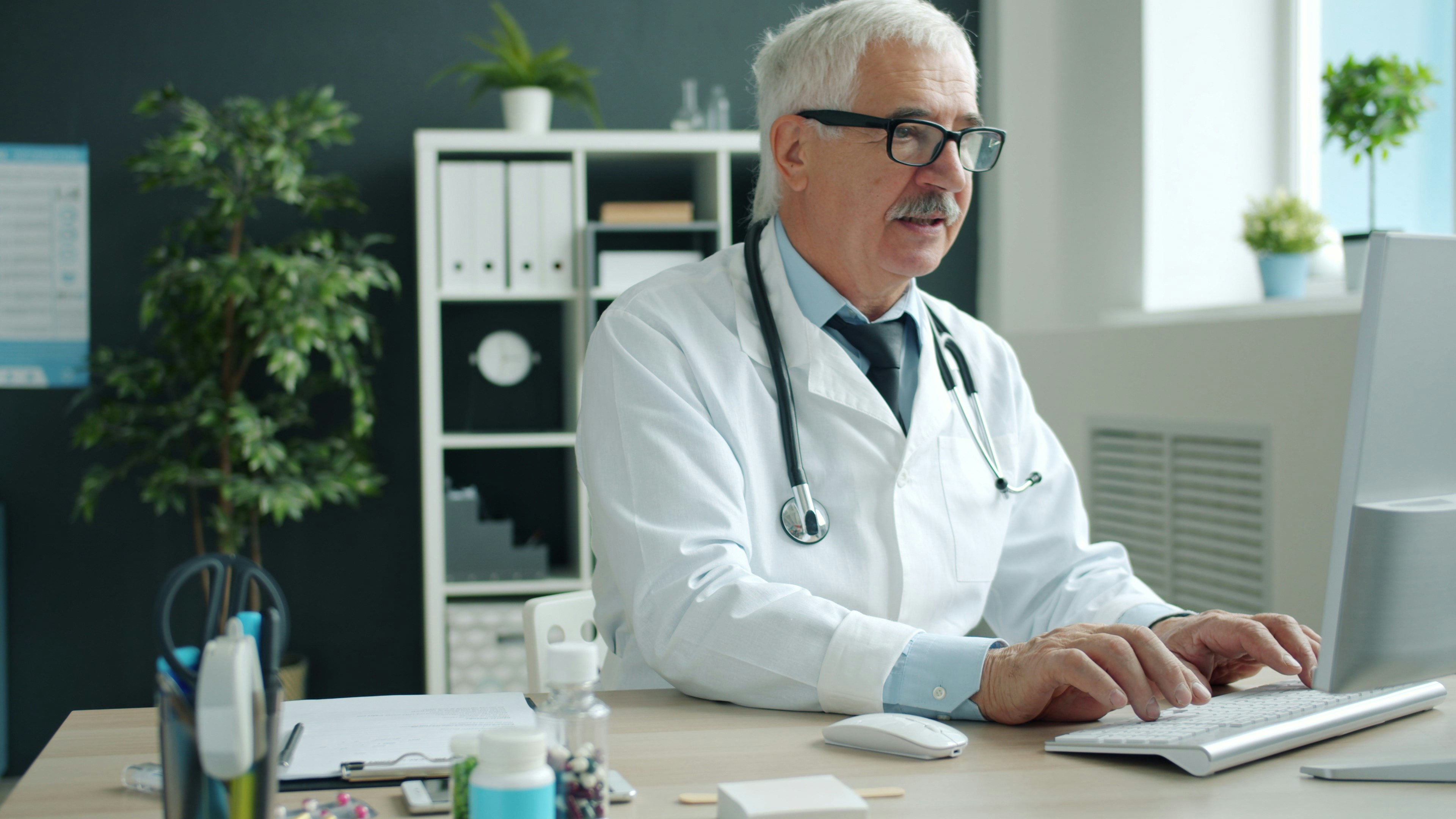 M&eacute;dico usando computador em consult&oacute;rio